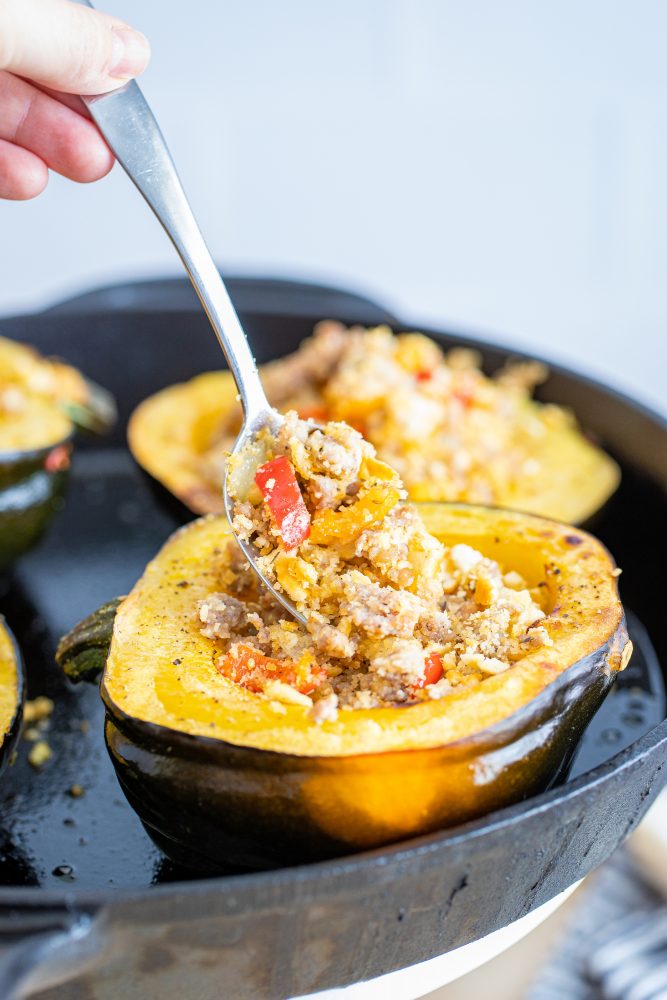 Sausage-stuffed acorn squash in a skillet, ready for the final bake.
