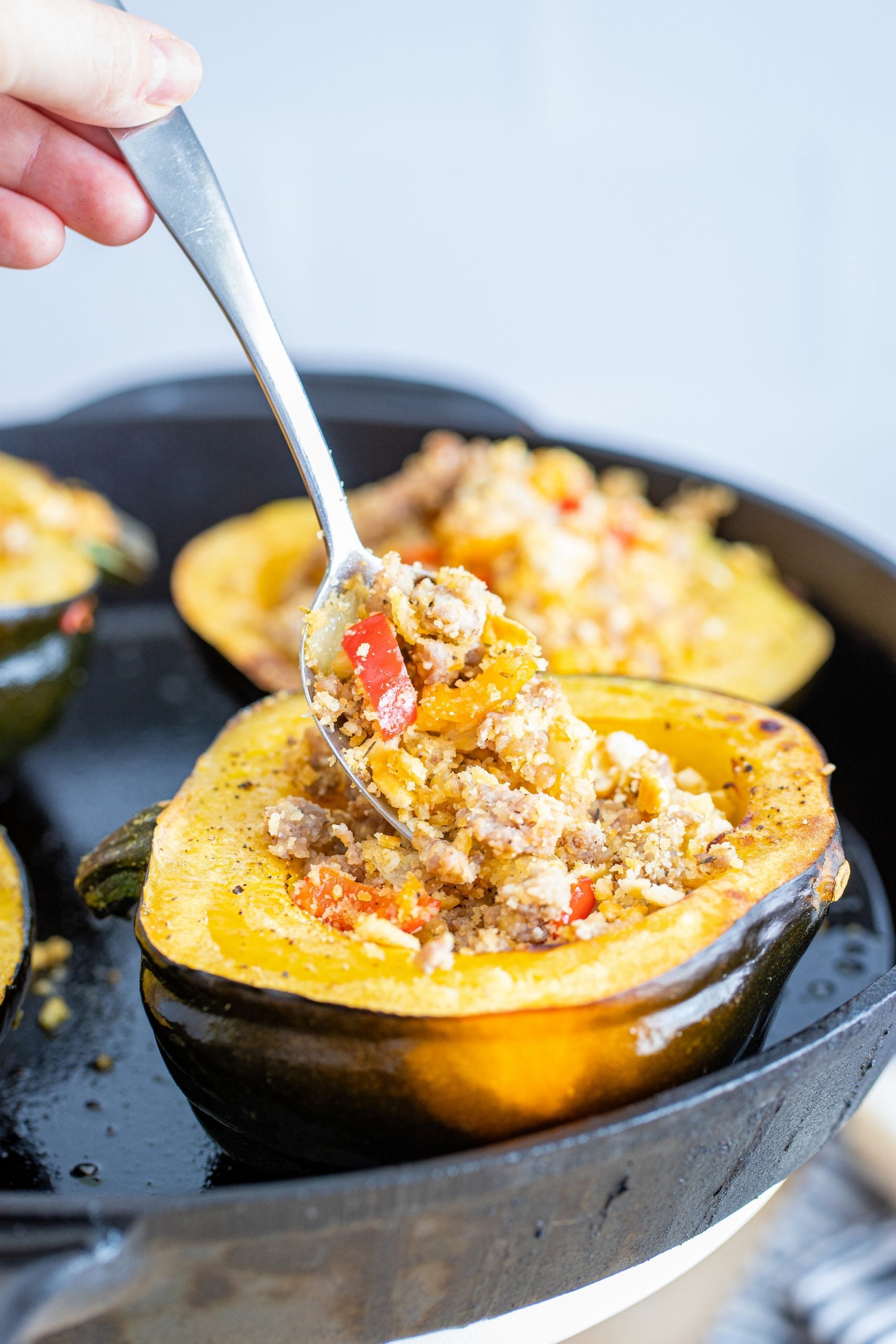 Sausage stuffed acorn squash in a skillet.