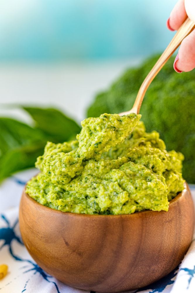 green pesto in a wooden bowl with a spoon