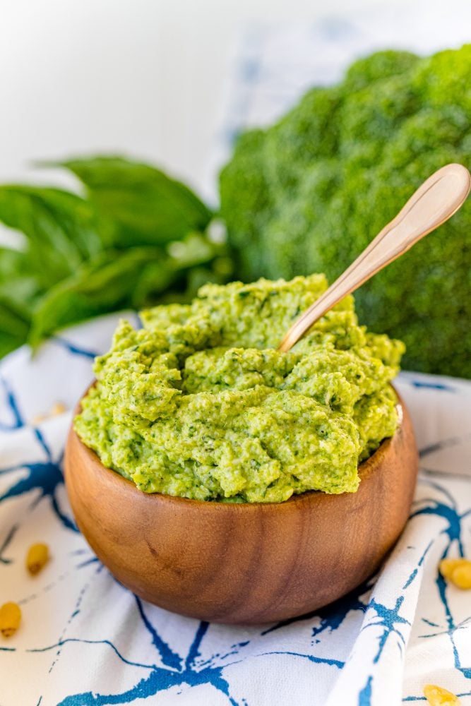 green pesto in a wooden bowl with a spoon