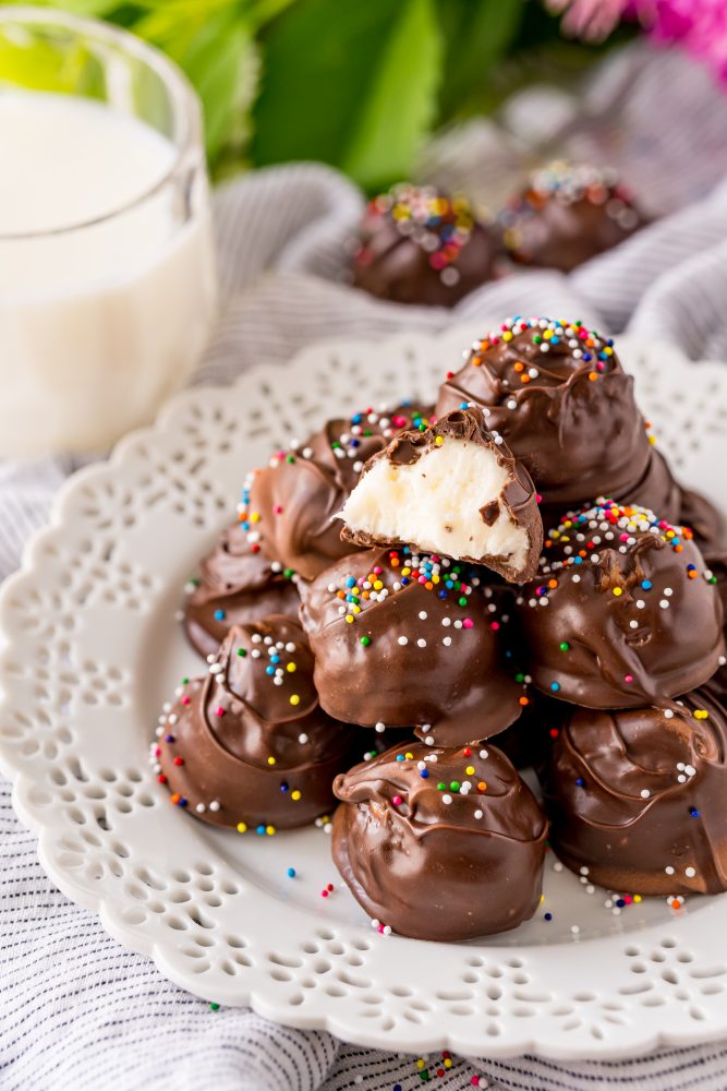 buttercream candies dipped in chocolate with sprinkles on a white plate 