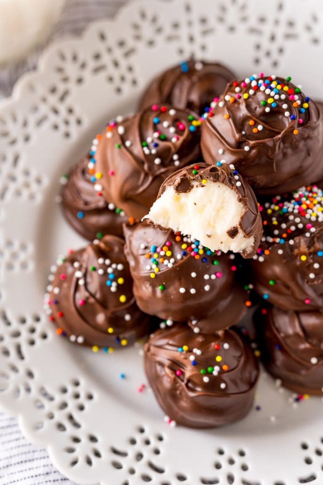 buttercream candies dipped in chocolate with sprinkles on a white plate 