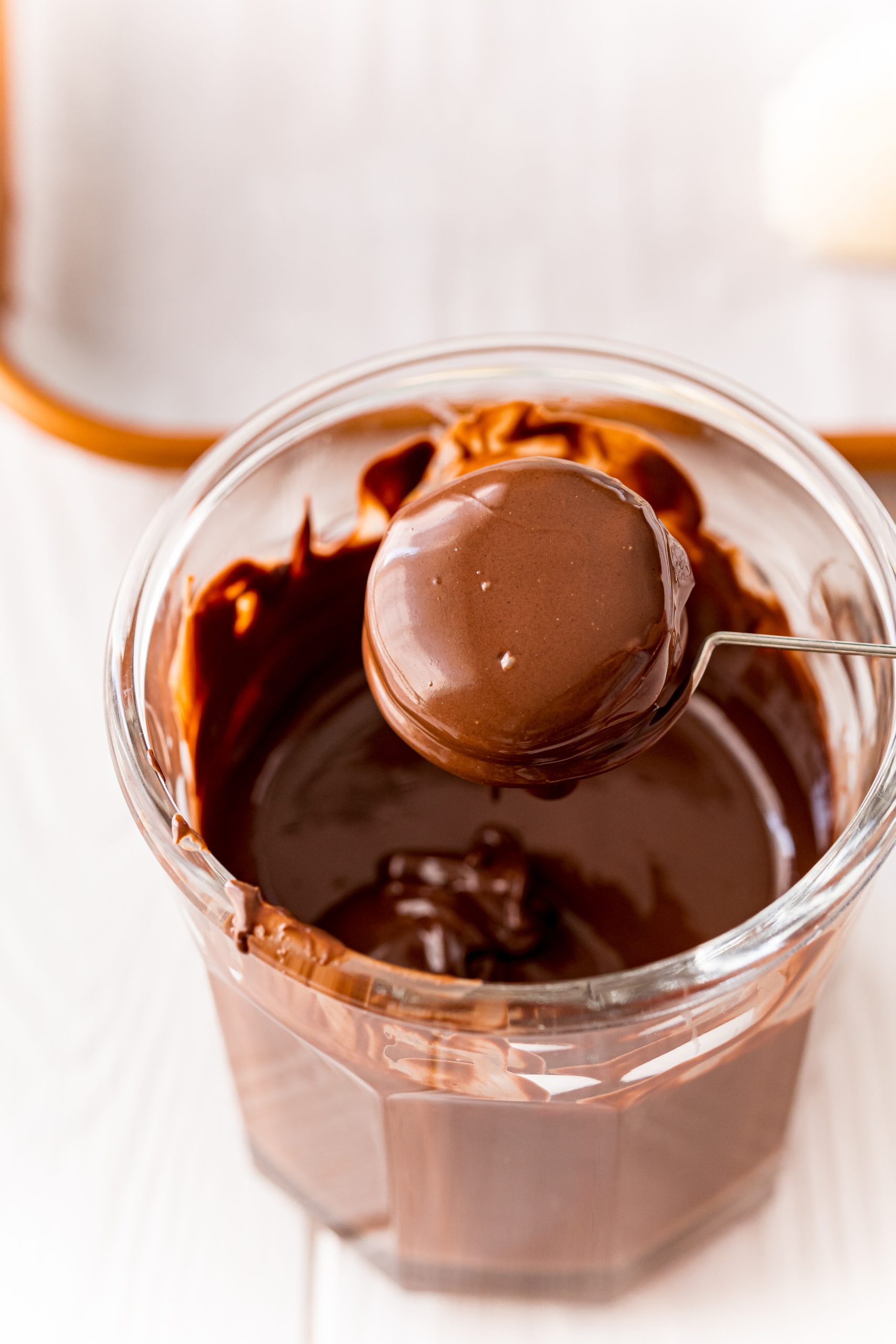 A bowl of chocolate ganache with a spoon and butter cream truffles on top.