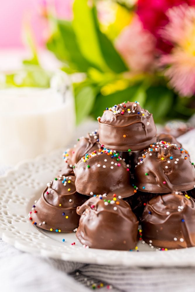 buttercream candies dipped in chocolate with sprinkles on a white plate 