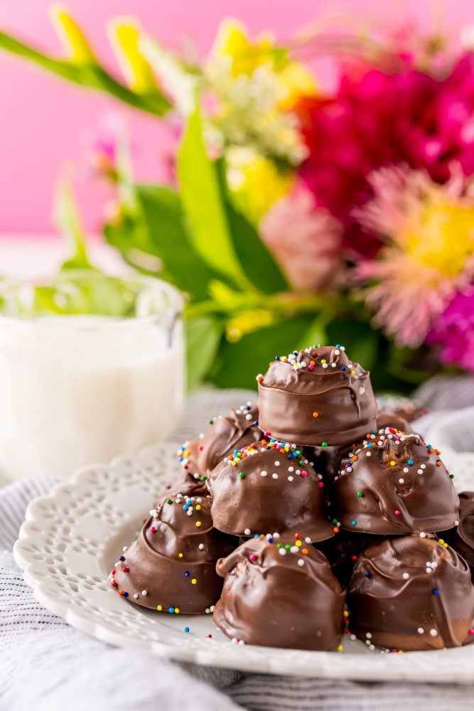 buttercream candies dipped in chocolate with sprinkles on a white plate 