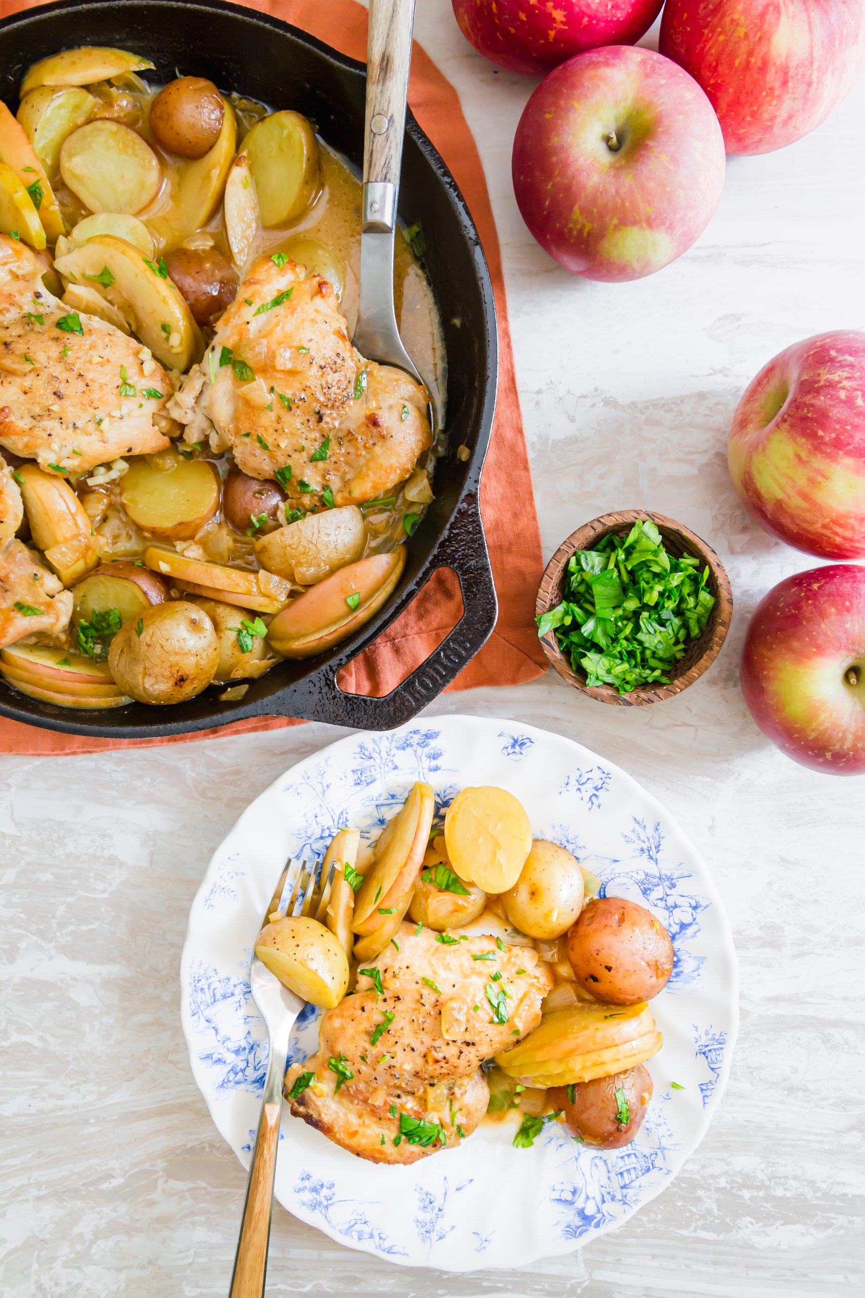 picture of chicken thigh, potatoes, apple slices in a mustard sauce on a plate 