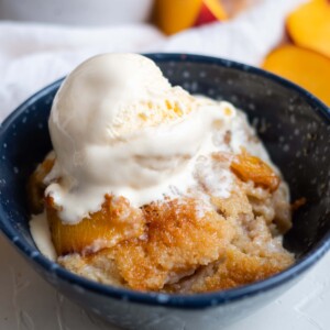 Easy peach cobbler served in a bowl with ice cream.