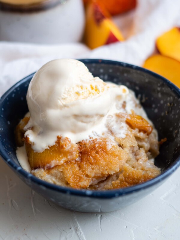 Easy peach cobbler served in a bowl with ice cream.