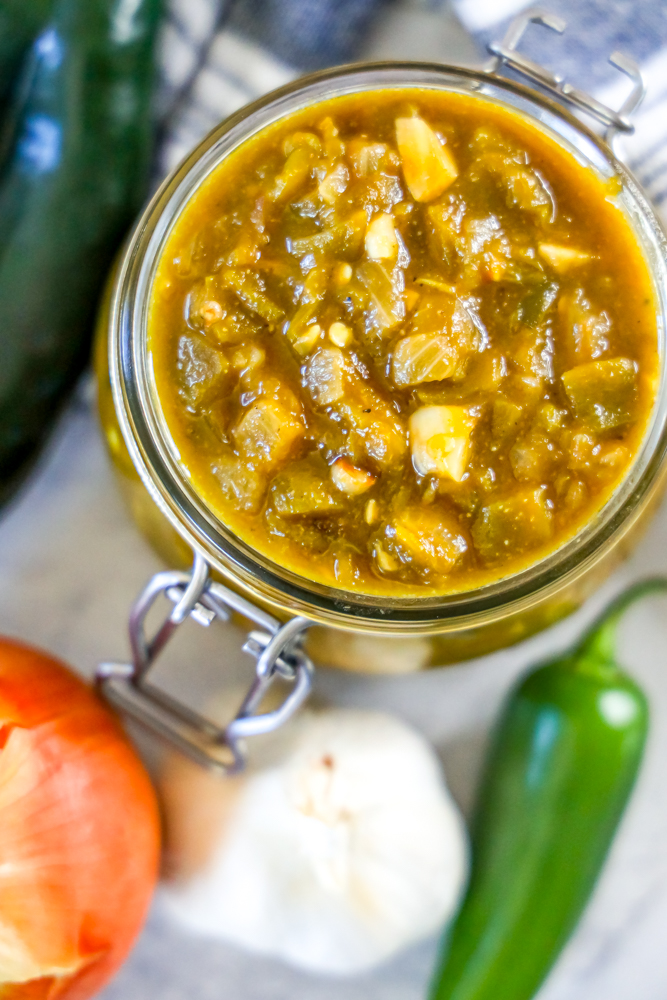 green chile sauce in a jar and a spoonful of green chile sauce in front of it
