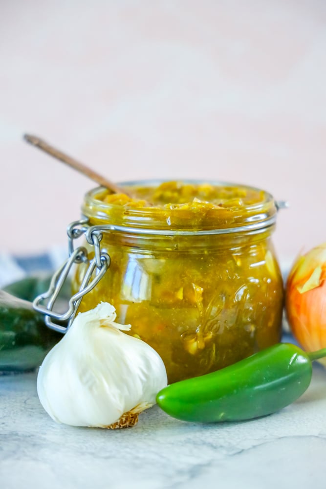 green chile sauce in a jar and a spoonful of green chile sauce in front of it