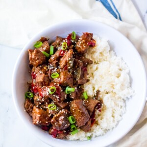 A bowl of easy instant pot Korean beef and rice in front of a blue tablecloth.