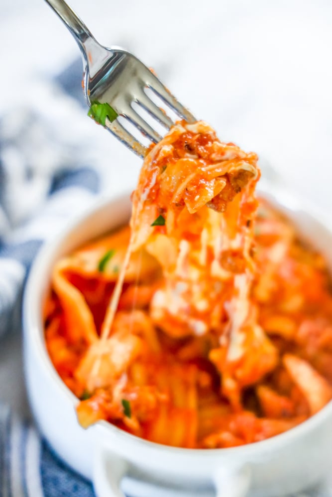 picture of fork lifting skillet lasagna from a white bowl
