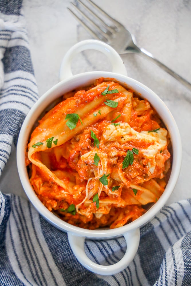 a skillet of lasagna noodles, sauce, and mozzarella cheese with parsley on it