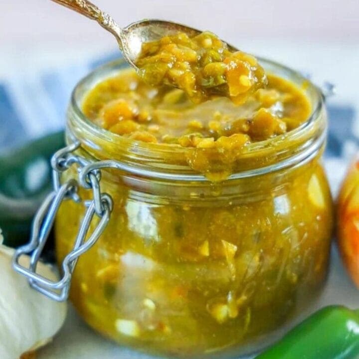 green chile sauce in a jar and a spoonful of green chile sauce in front of it