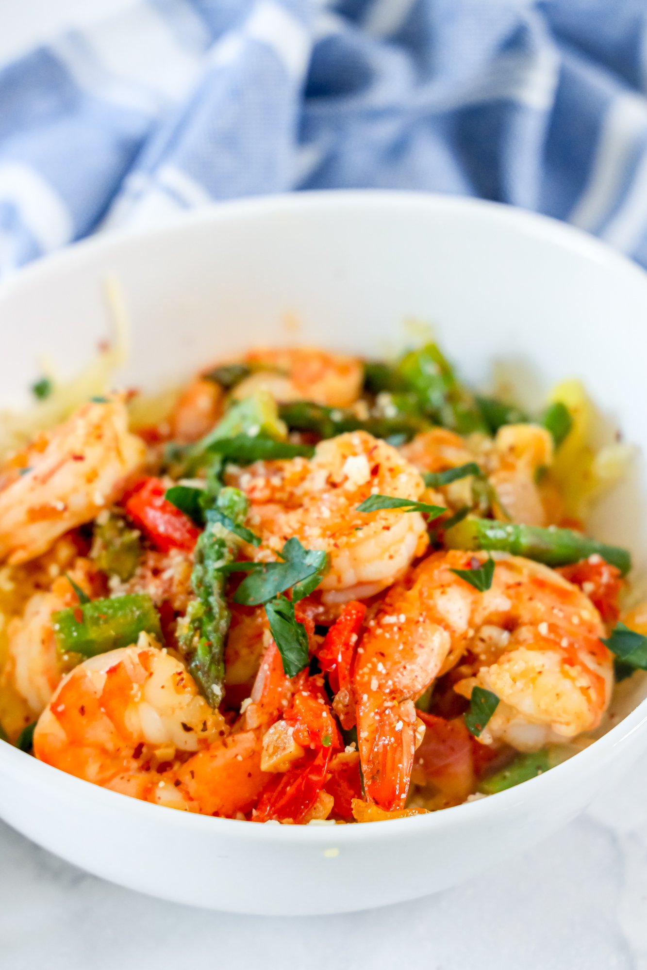 picture of shrimp and asparagus over spaghetti squash noodles in a white bowl 