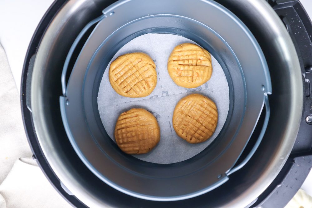 picture of raw pumpkin butter cookies in an air fryer lined with parchment paper