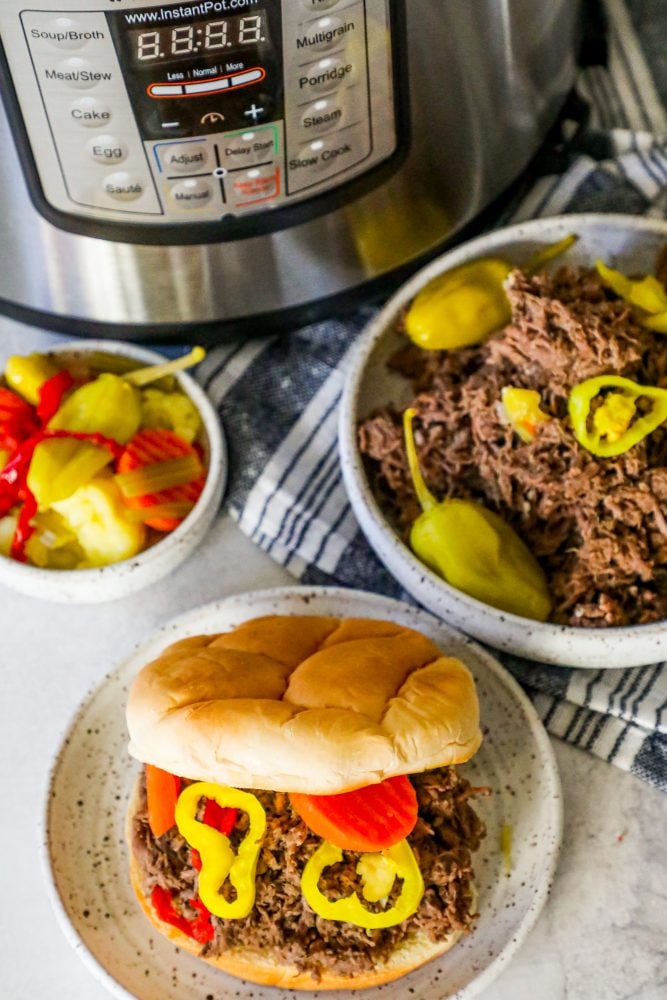 Picture of Italian shredded beef in a white bowl in front of an instant pot