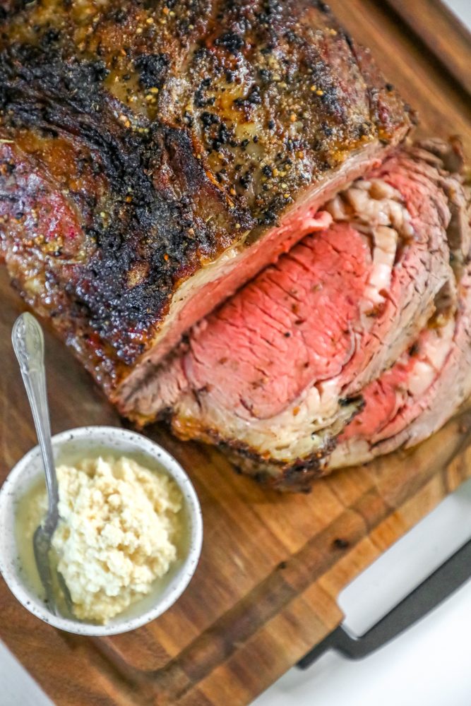 picture of ribeye roast on a wood cutting board next to bowl of horseradish 
