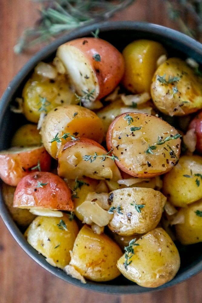 roasted potatoes in a bowl with herbs and butter