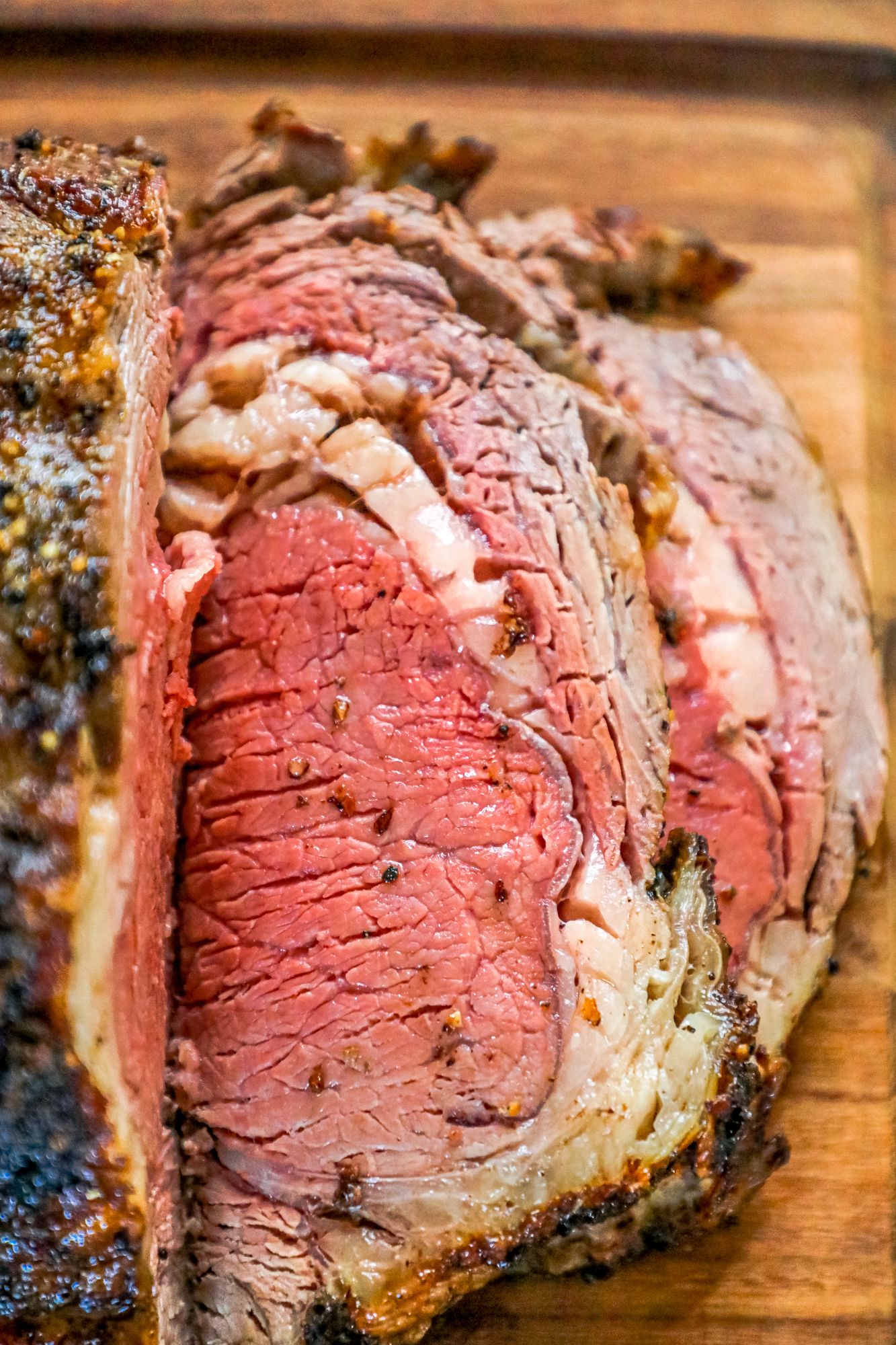 A flavorful ribeye roast sliced and displayed on a rustic wooden cutting board.
