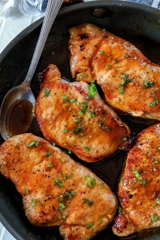 pork chops in a pan with brown sugar sauce 