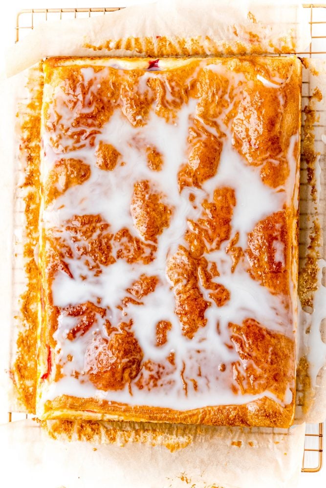 glazed cherry cheesecake pastry on a cooling rack on a table