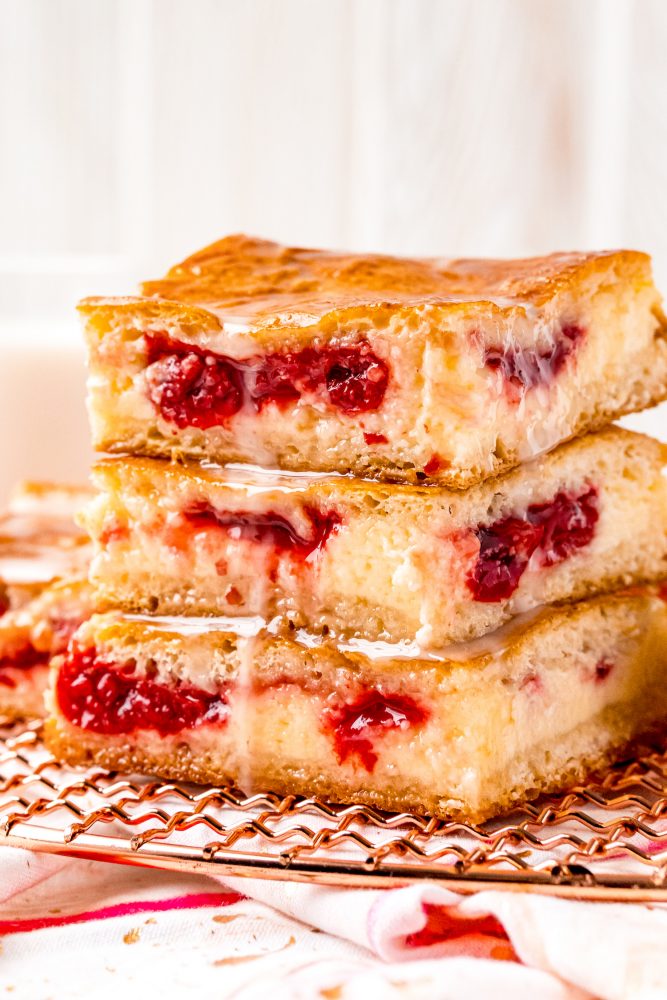 baked cherry danish pastry bars with a vanilla glaze stacked on a wire rack