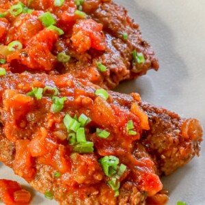 A plate of chicken breasts with tomato sauce.