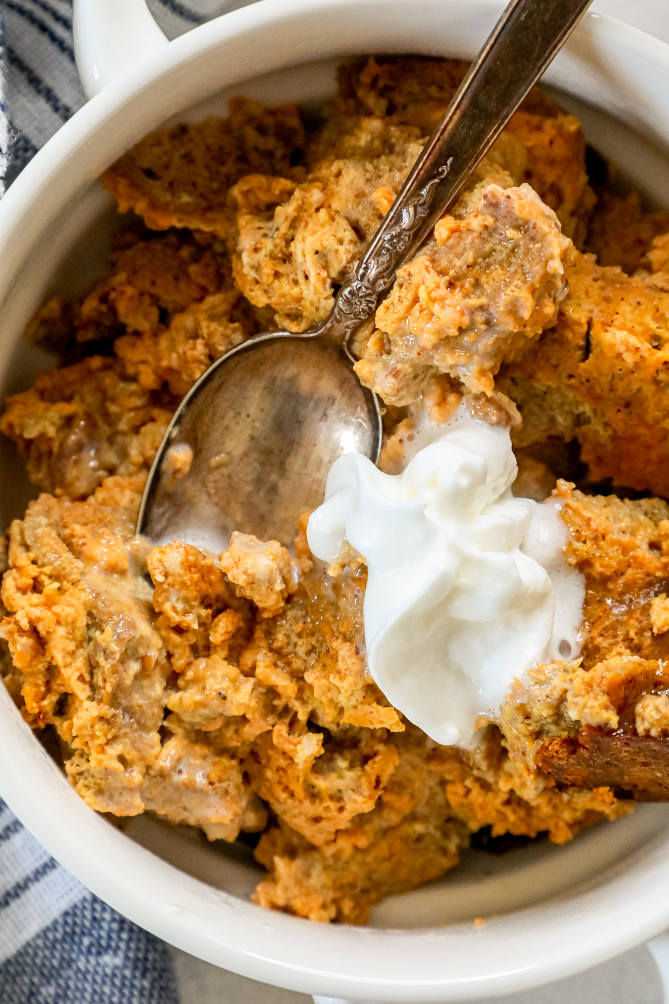 Slow Cooker Keto Pumpkin Bread Pudding served in a white bowl with sour cream garnish.