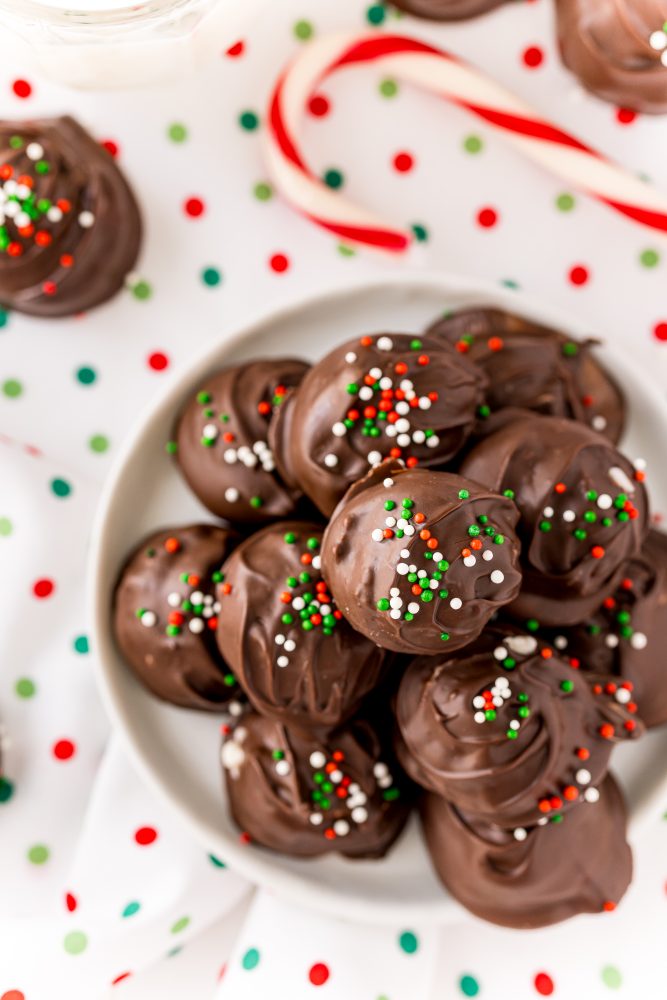 a pile of chocolate buttercream candies with green, white, and red sprinkles on a white plate