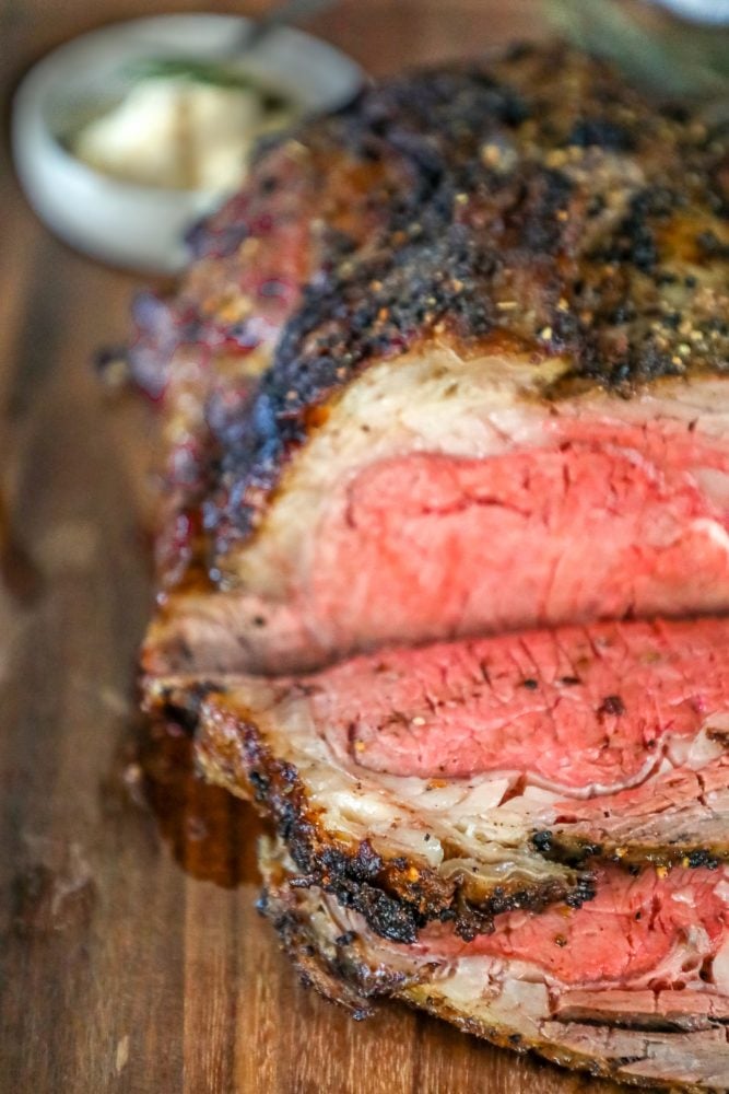 picture of ribeye roast on a wood cutting board next to bowl of horseradish 