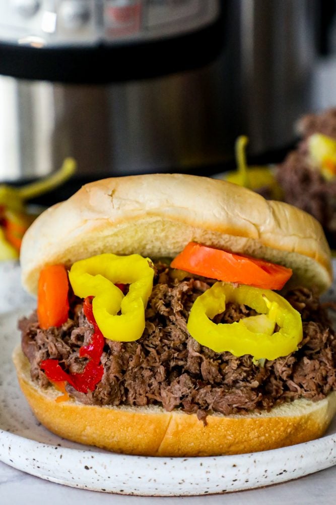 Picture of Italian shredded beef in a white bowl in front of an instant pot