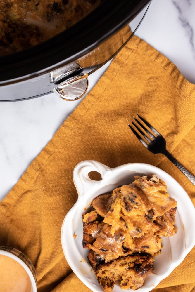 picture of pumpkin bread pudding next to a slow cooker with whipped cream on a fork 
