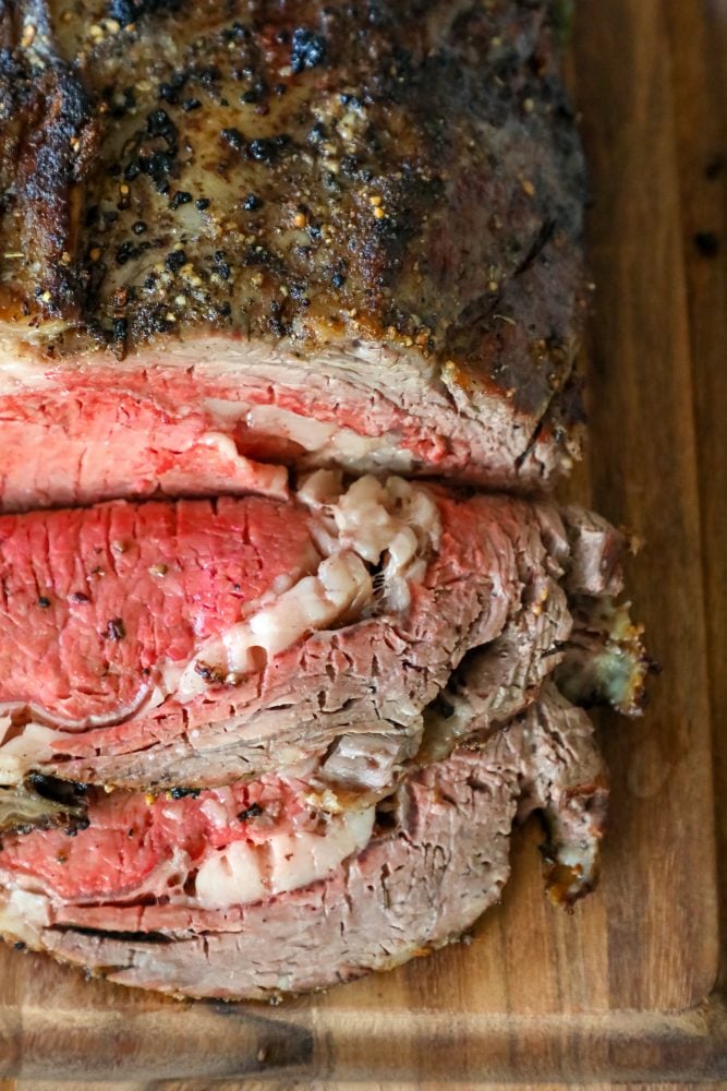 roasted prime rib sliced on a wood cutting board