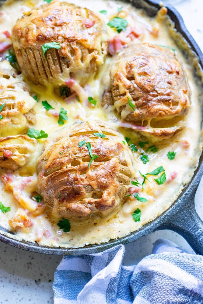 4 hasselback potatoes in gratin sauce in a cast iron skillet.