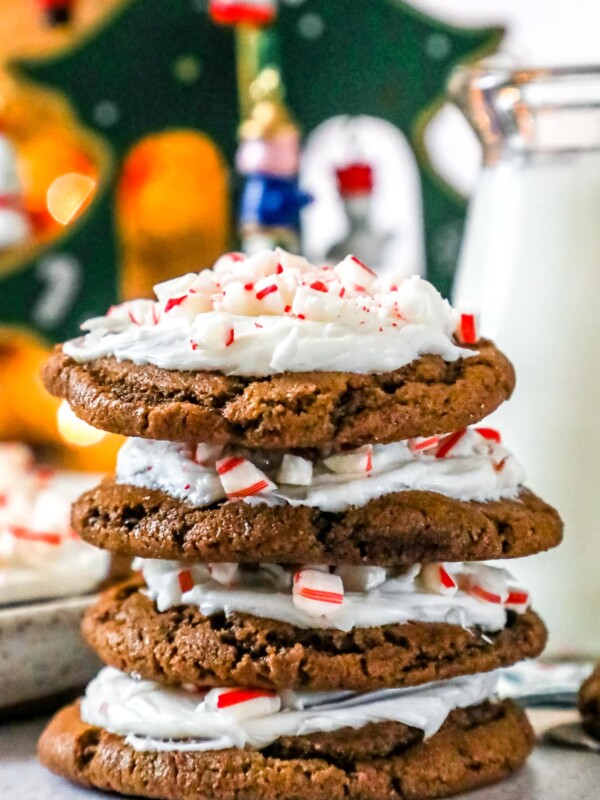 A stack of iced peppermint chocolate cookies with whipped cream and candy canes.