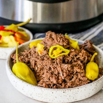 picture of shredded italian beef with banana pepper rings and pepperoncini pepper in front of an Instant pot