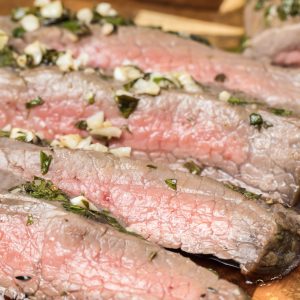 A flavorful London broil made with garlic and herbs, displayed on a cutting board.