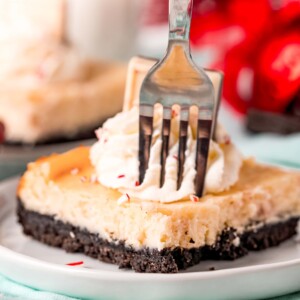 A peppermint cheesecake slice on a plate with a fork.