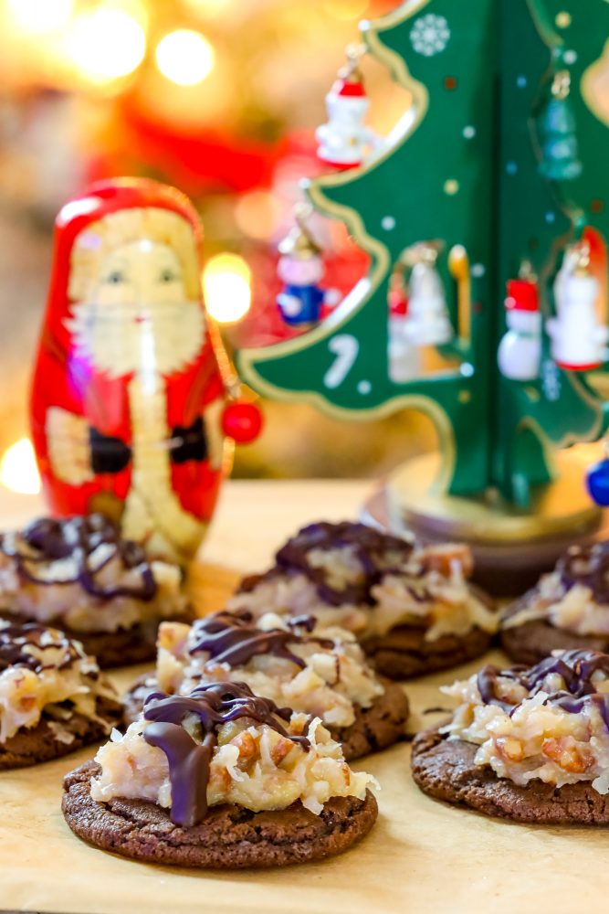 German chocolate iced chocolate cookies on a piece of parchment paper on a table in front of Christmas decorations