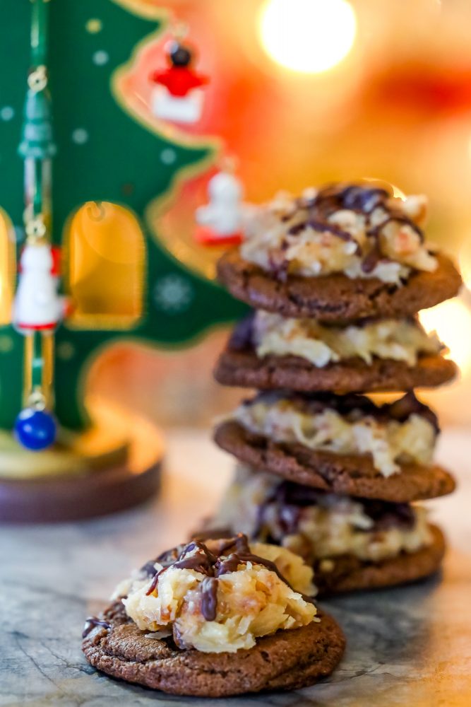 Chocolate cookies topped with coconut and chocolate German topping stacked on top of each other 