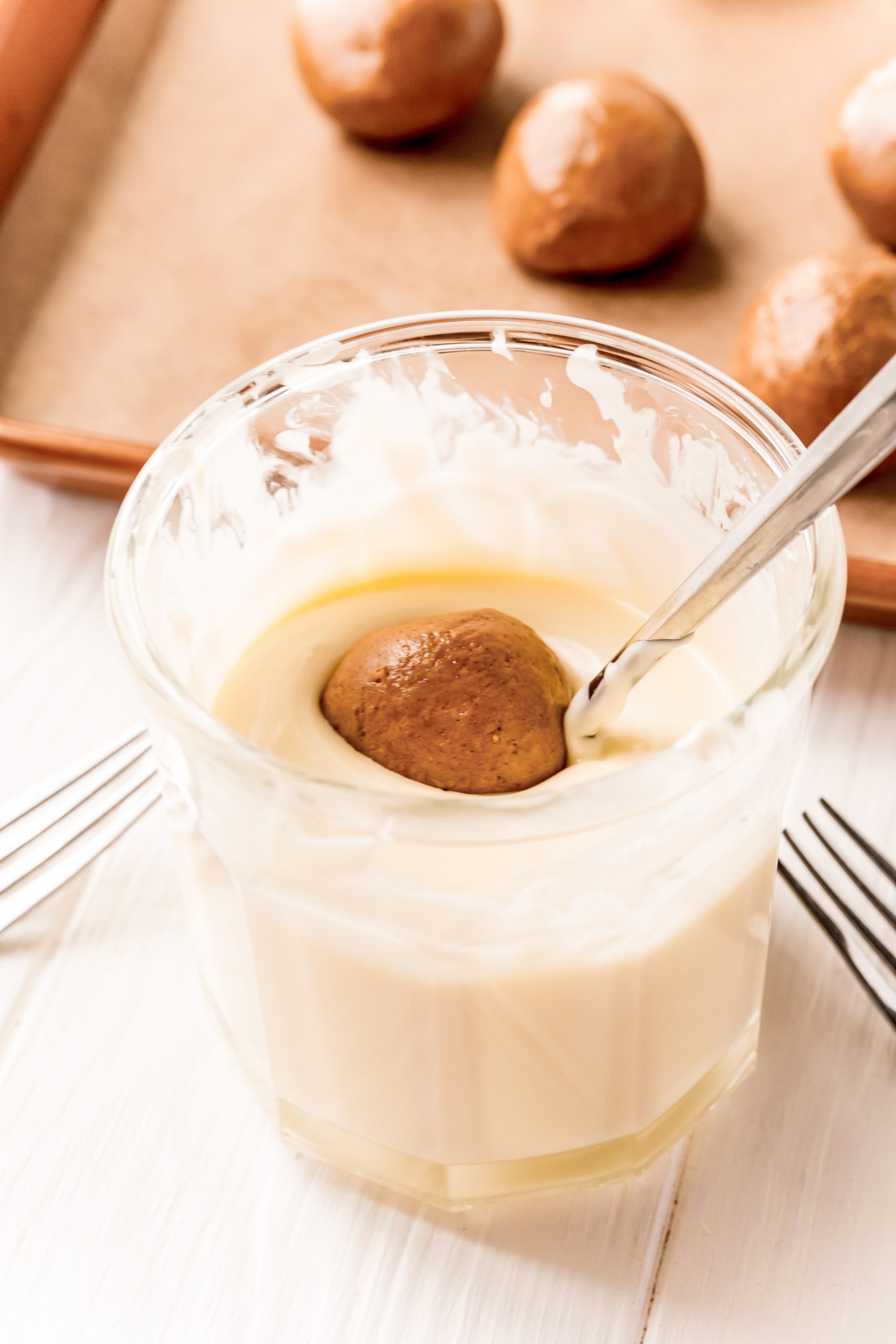 A bowl of gingerbread truffles with a spoon next to a bowl of doughnuts.