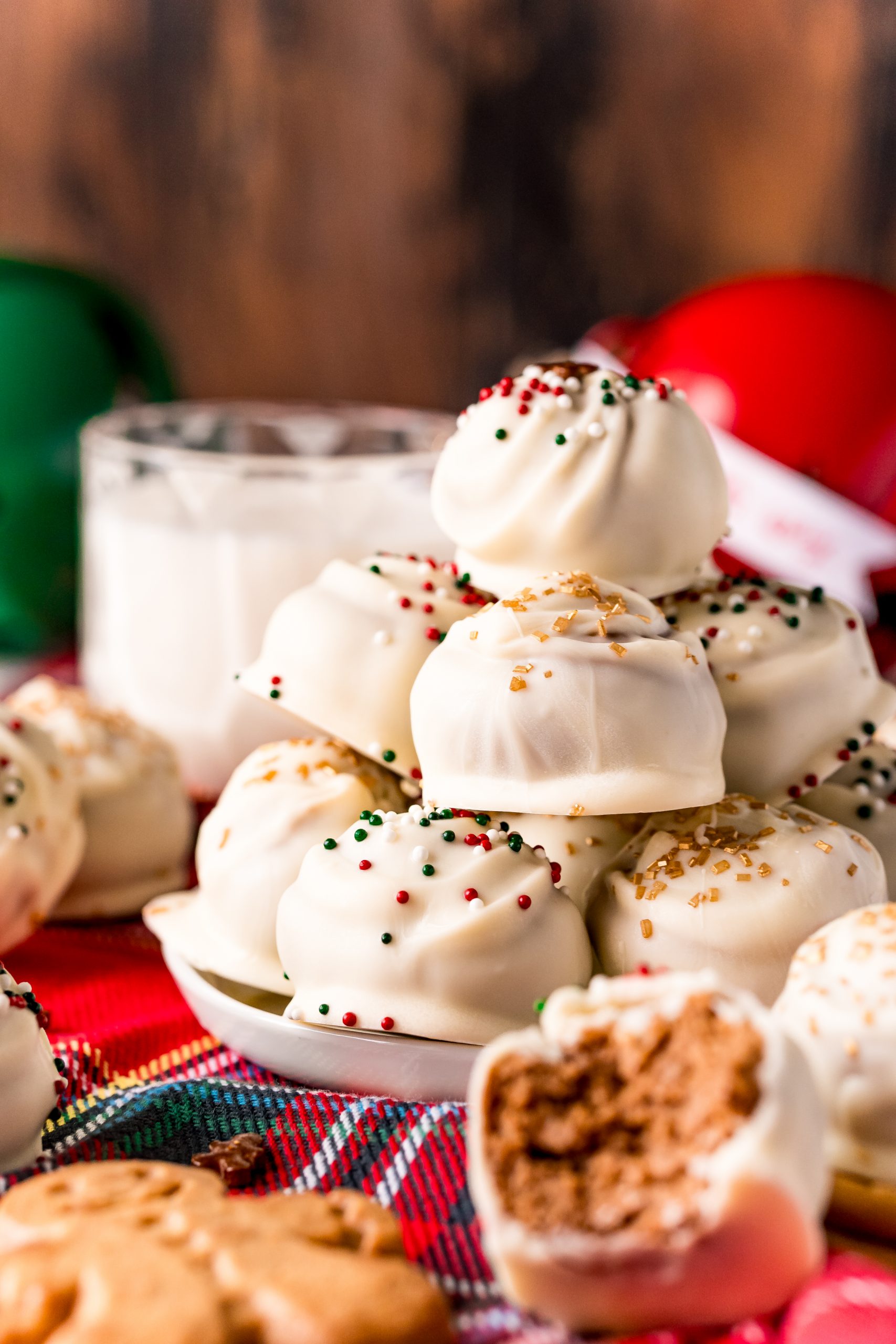 A stack of gingerbread truffles with white frosting on a red tablecloth.