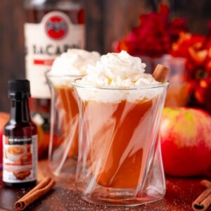 Two glasses of apple cider with whipped cream and cinnamon, hot cider.