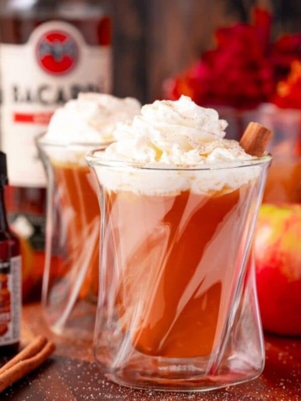 Two glasses of apple cider with whipped cream and cinnamon, hot cider.