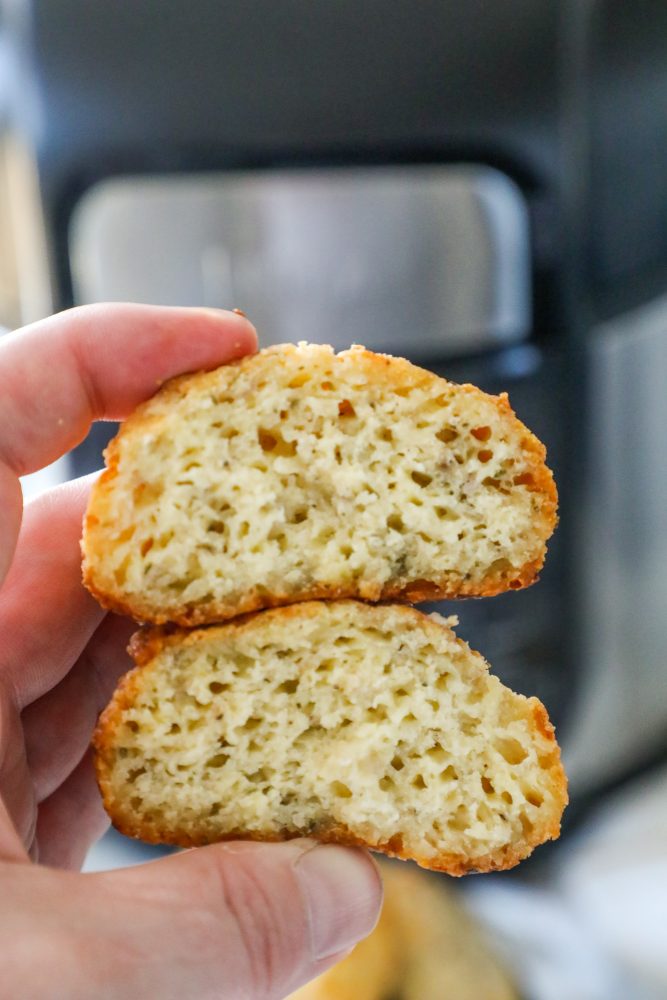 keto cheesy bread roll held by a person in front of an air fryer