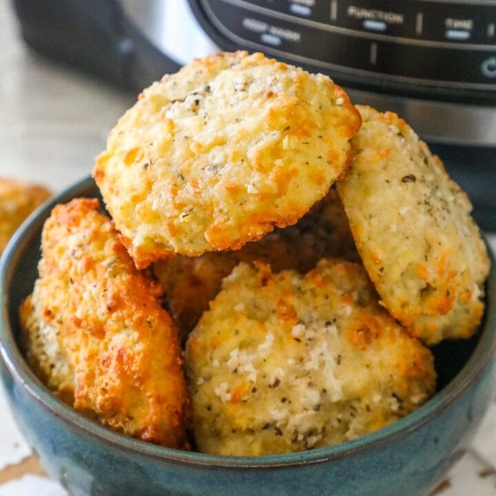 a bowl of rolls stacked in a blue bowl in front of an air fryer machine