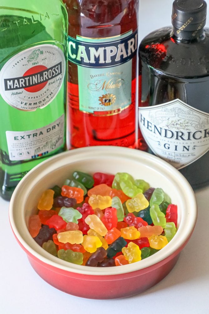 a bowl of gummy bears with gin, vermouth, and campari in the background