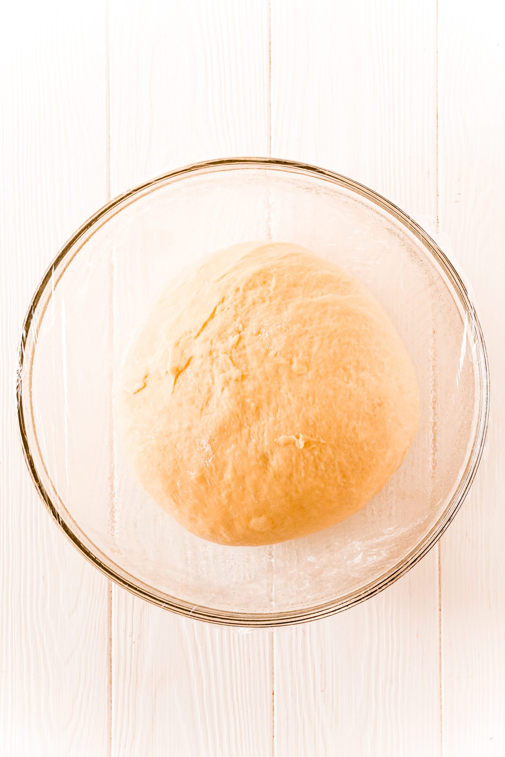 picture of roll dough in a bowl wrapped with plastic wrap