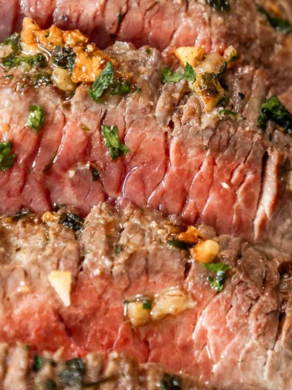 A close up of a broiled top round steak seasoned with garlic and herbs.